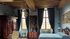 A traditional room with a bed, wooden furniture, a chandelier, and a large window with curtains. - Château de La Rivière (Pontgouin)