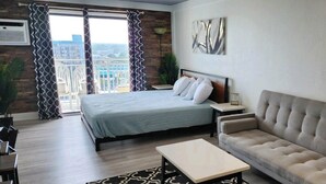 A modern hotel room with a large bed, a sofa, a coffee table, and a view of the city. - Beach Life Oceanview Efficiency DW 1503 (Myrtle Beach)