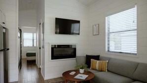 Ein modernes Wohnzimmer mit Kamin, einer Couch, einem Couchtisch und einem an der Wand befestigten Fernseher.