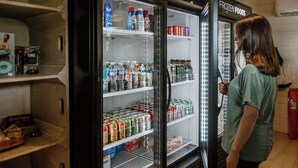 A refrigerated display case with various beverages and snacks, including bottled water, sodas, and packaged foods.