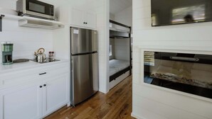 A compact kitchen with a stainless steel refrigerator, a microwave, and a coffee maker on the countertop.