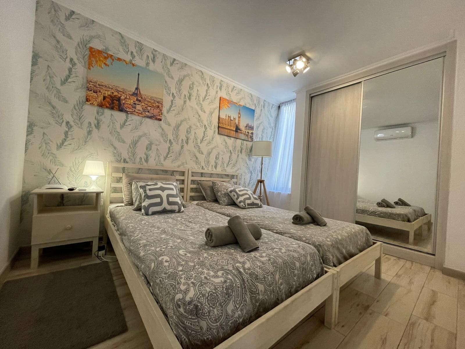 A bedroom with a bed, nightstands, a mirror, and artwork on the wall.