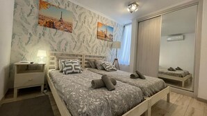 A bedroom with a bed, nightstands, a mirror, and artwork on the wall.