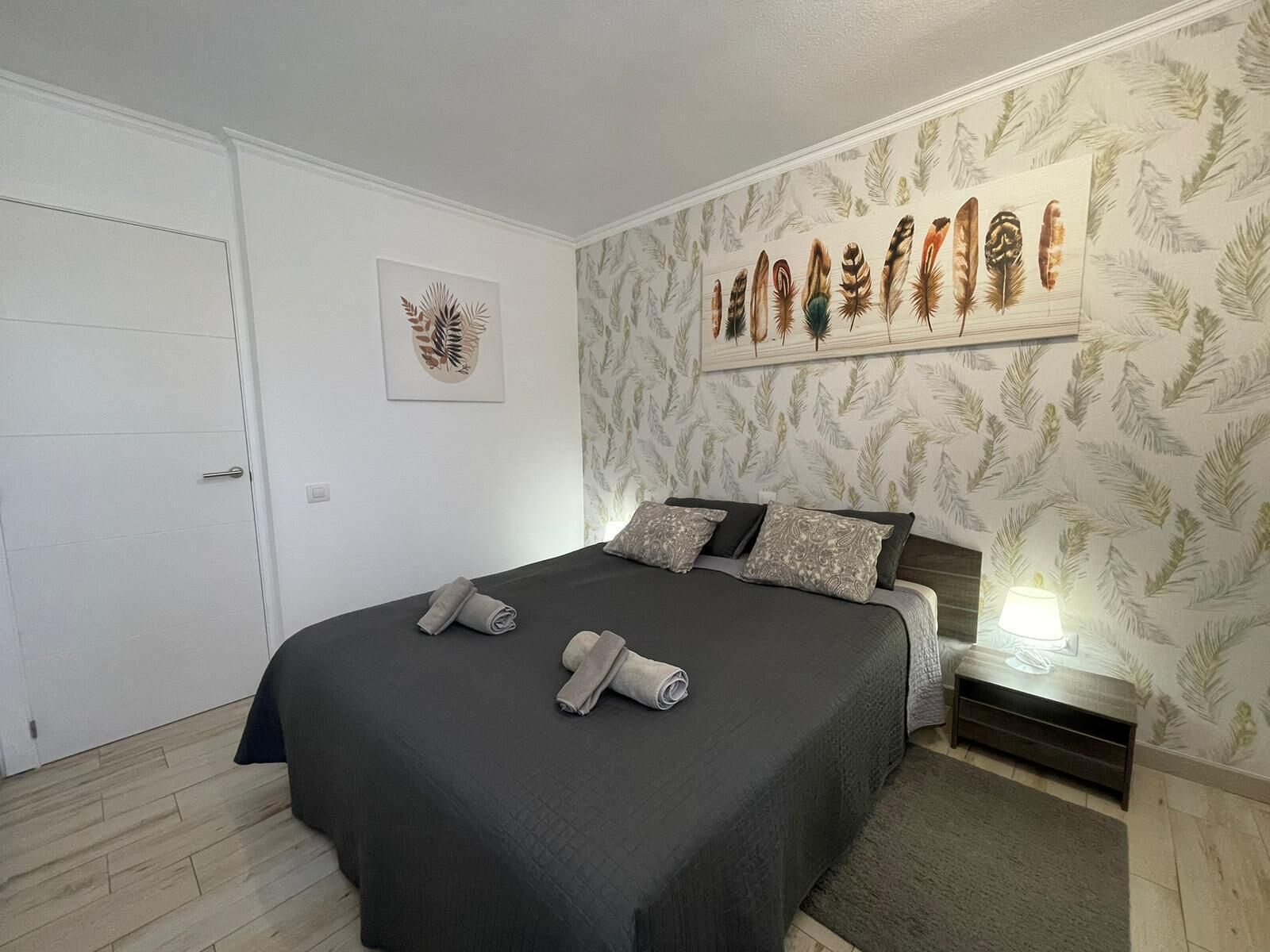 A neatly arranged bedroom with a bed, pillows, and a wall-mounted artwork.