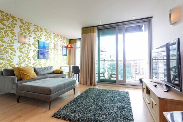 Una sala de estar moderna con un sofá, un televisor y un balcón con vistas.