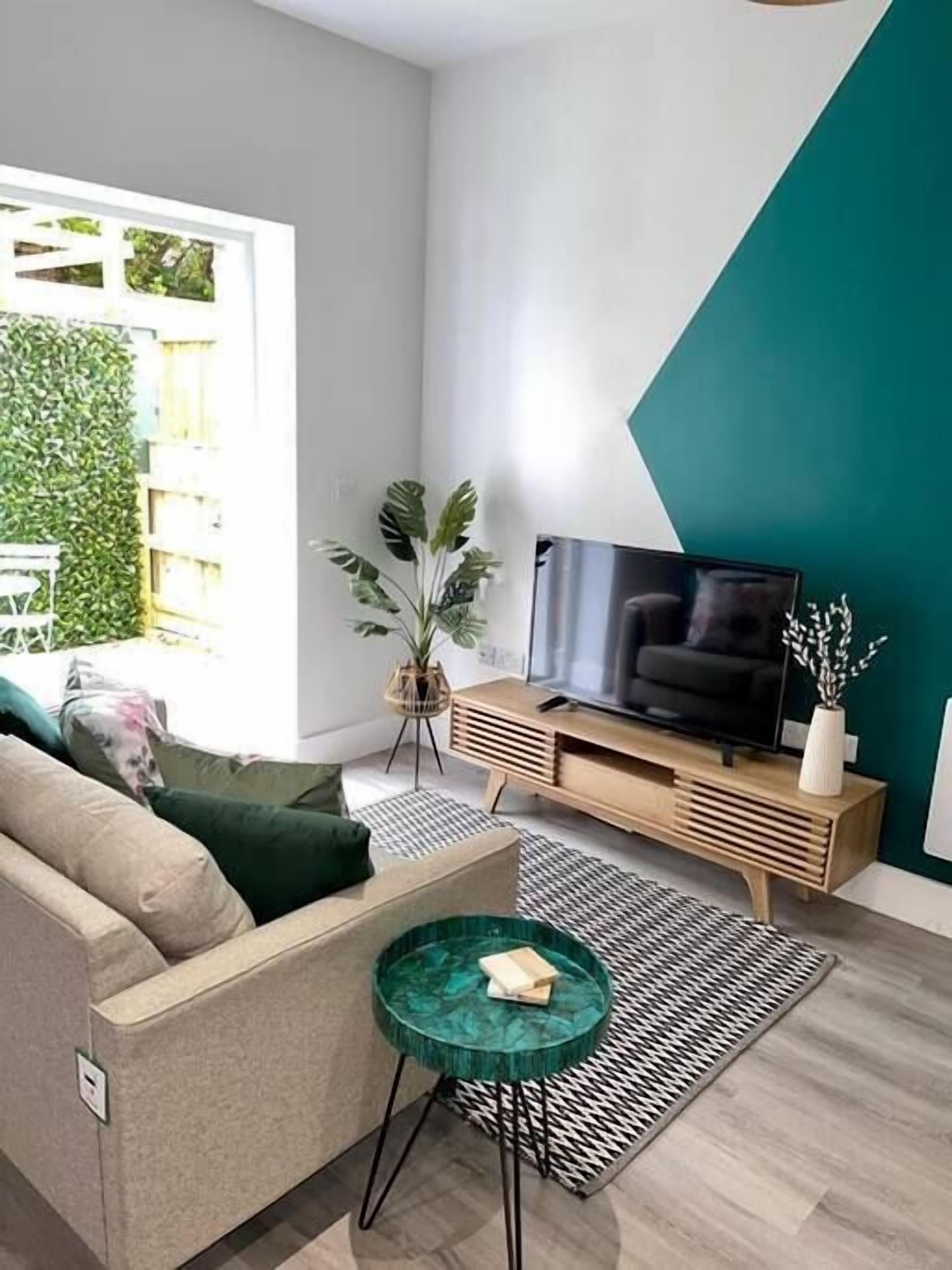 A modern living room with a sofa, a coffee table, a TV, and a plant.