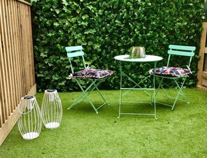 A small outdoor seating area with two green chairs and a table, surrounded by a lush green hedge. - Gorgeous New 1-Bed, Town Centre, Parking & Garden (Bournemouth)