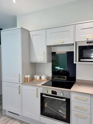 A modern kitchen with white cabinetry, a black stove, and a microwave.