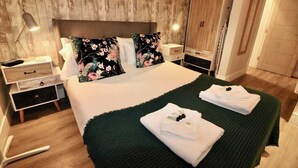 A neatly made bed with floral pillows, a green throw blanket, and folded towels. - Large Studio Apt, Close to Beach w/ Free Parking! (Bournemouth)