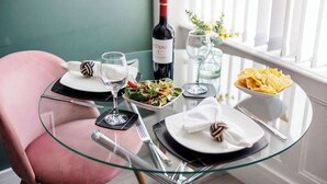 A dining table with a bottle of wine, glasses, plates, and a bowl of chips. - Light, Bright & Full of Style. 1-Bed Apt with PKG (Bournemouth)