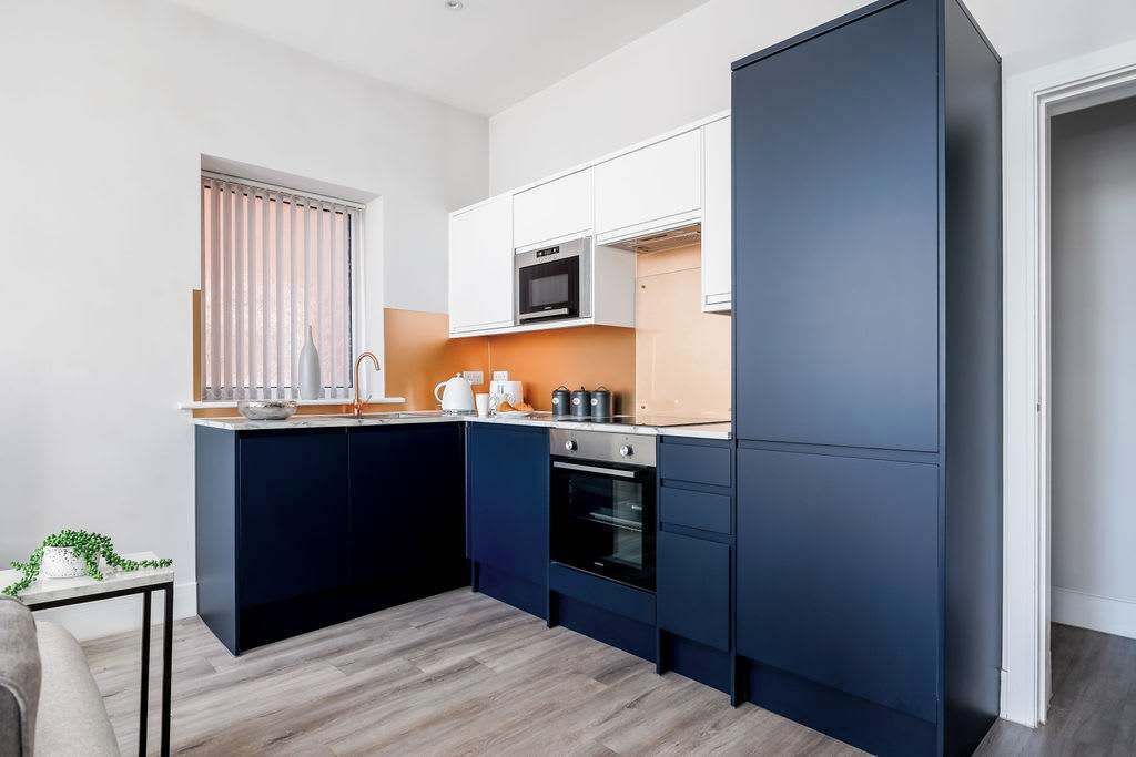 A compact kitchen with dark cabinetry, a microwave, an oven, and a small countertop area.