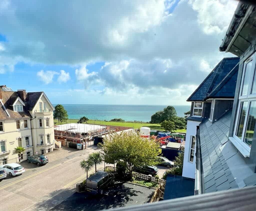 A coastal view with a building overlooking the sea, a parking area, and a construction site.