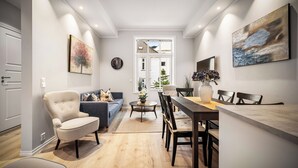 Ein modernes Wohnzimmer mit einer Couch, einem Sessel, einem Esstisch und Stühlen.