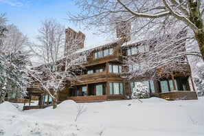 A multi-story wooden building with large windows and a snow-covered landscape.