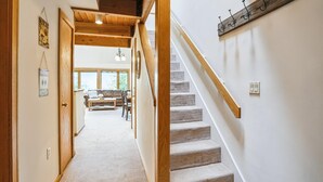 A hallway with a staircase, wooden beams, and a wall-mounted coat rack. - Ski-in 1 bedroom plus loft condo with pool, hot tub, and fireplace. (Killington)