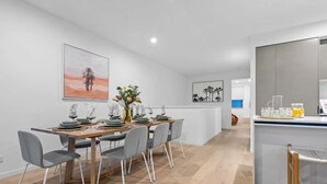 A modern dining area with a wooden table, grey chairs, and a central vase with flowers.