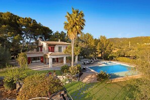 A two-story house with a swimming pool, surrounded by lush greenery and a clear blue sky. - Villa Finca Estel (Calvia)