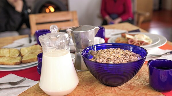 Une table de petit-déjeuner avec un pot à lait, un bol de céréales et des assiettes de toasts.