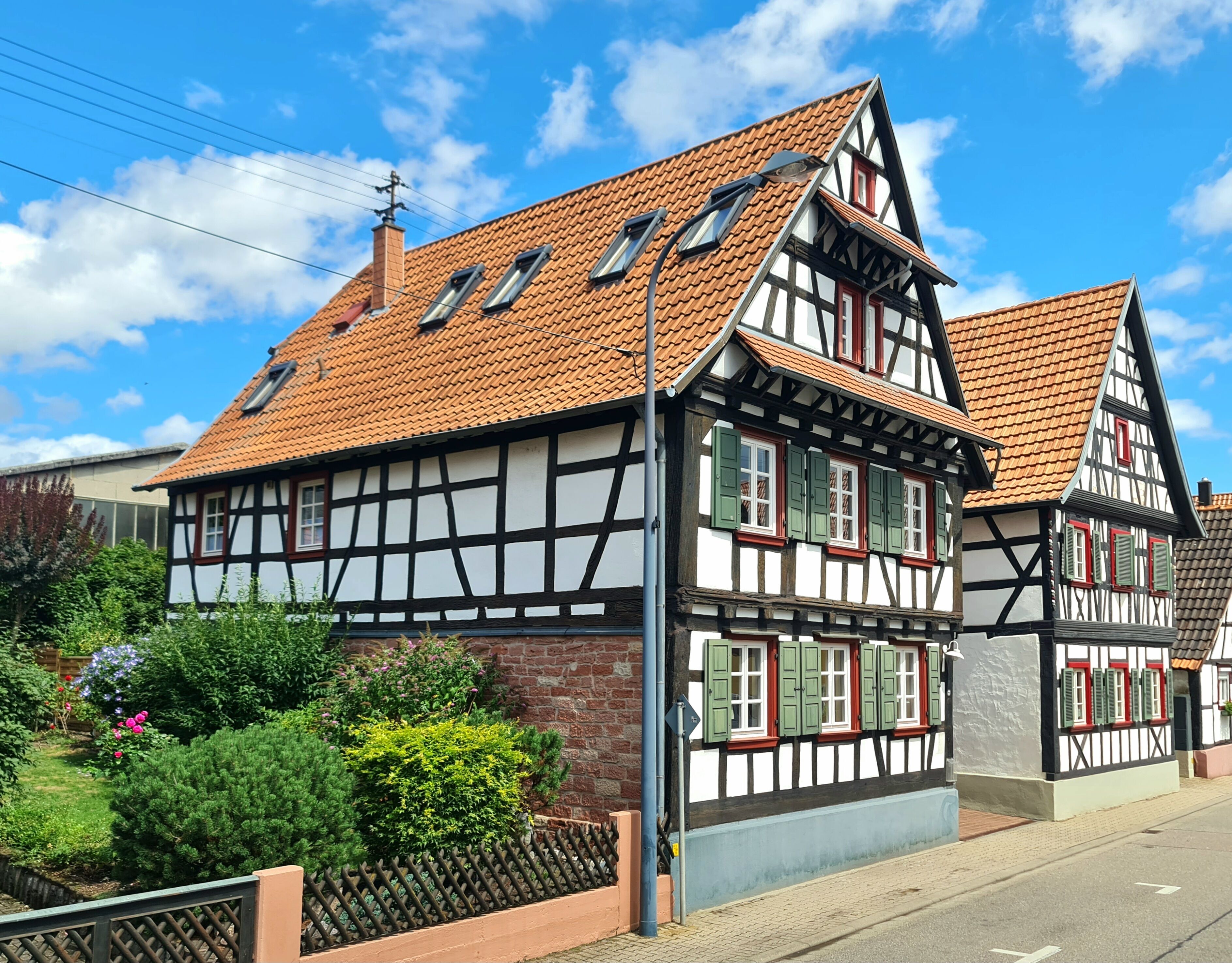 A traditional half-timbered house with a sloped roof, multiple windows, and a brick foundation.