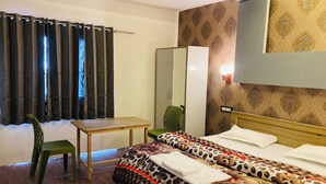 A hotel room with a bed, a desk, a chair, a mirror, and a red rug. - Sizzling Resort And Adventure (Dhanaulti)