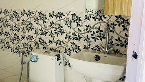 A bathroom with a toilet, bidet, and sink. The walls have a floral tile pattern. - Sizzling Resort And Adventure (Dhanaulti)