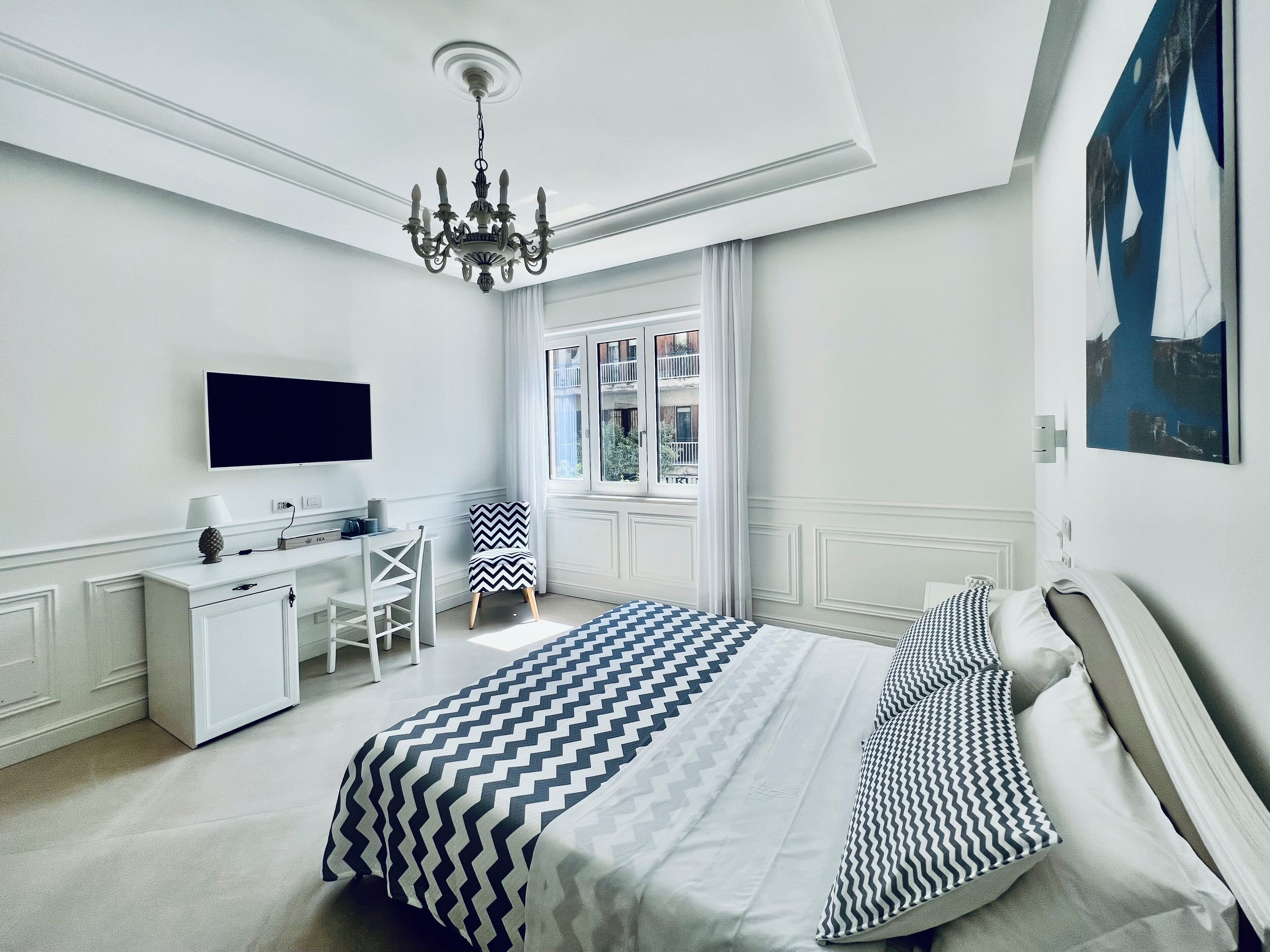A modern bedroom with a large bed, a desk, and a chair.