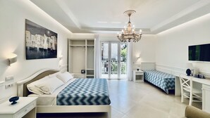 A modern bedroom with a large bed, a desk, and a TV. There is a balcony with a view of the city. - Palazzo Mauro Sorrento Luxury Rooms (Sorrento)