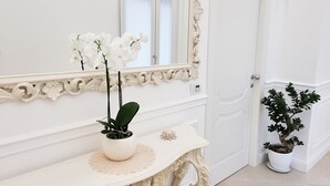 A white ornate console table with a mirror and a potted orchid. - Palazzo Mauro Sorrento Luxury Rooms (Sorrento)