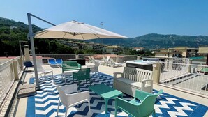 Une terrasse sur le toit avec des sièges extérieurs, une piscine et une vue sur le paysage environnant.