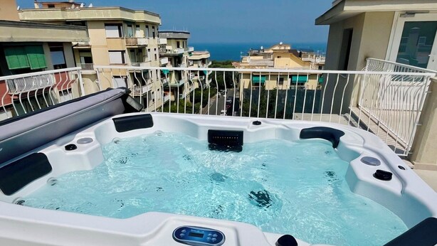 A hot tub on a balcony with a view of the sea and neighboring buildings. - Palazzo Mauro Sorrento Luxury Rooms (Sorrento)