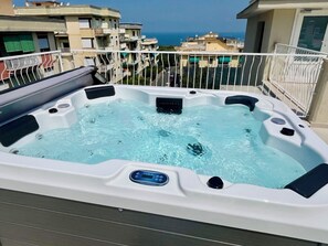 A hot tub on a balcony with a view of the sea and neighboring buildings. - Palazzo Mauro Sorrento Luxury Rooms (Sorrento)