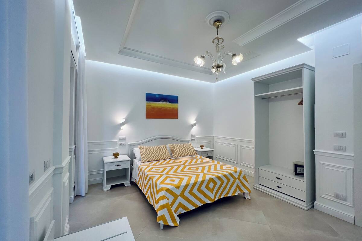 A bedroom with a bed, nightstands, a wardrobe, and a painting on the wall.