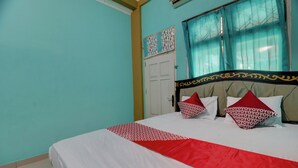 Ein Schlafzimmer mit Bett, Fenster mit Vorhängen und einer Tür.