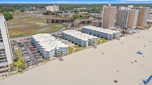 Un hôtel situé en bord de mer, composé de plusieurs bâtiments, doté d’une piscine et donnant accès à une plage.