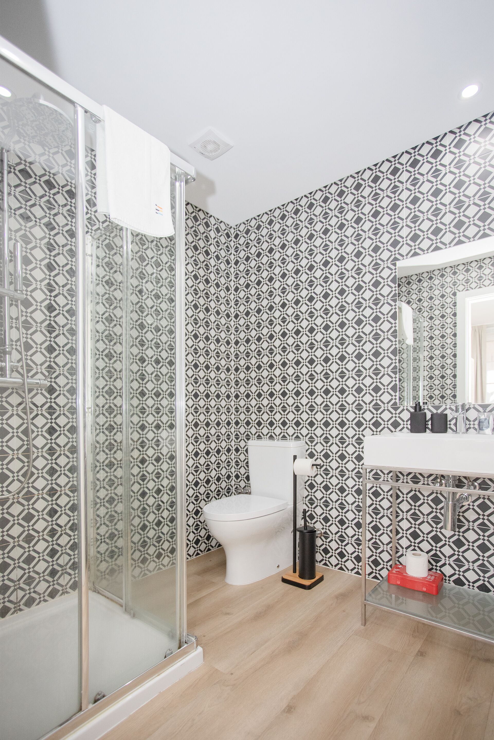 Een badkamer met een douchecabine van glas, een toilet en een wastafel met spiegel.