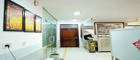 A hallway with a glass partition, a wooden door, and a refrigerator with a logo.