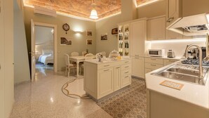 A modern kitchen with a central island, white cabinetry, and a brick ceiling.