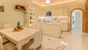 A modern kitchen with white cabinetry, a central island, and a dining area with a white table and chairs.