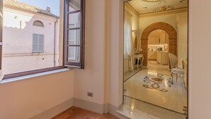 A room with a large window, a mirror, and a view of a building outside.