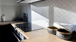 A modern kitchen with a black stove, two woven baskets on the counter, and a patterned backsplash. - New home Family Retreat near Pambula | 4bd 7guests (Broadwater)