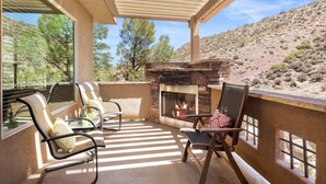 Un patio techado con chimenea de piedra, mobiliario exterior y vistas al paisaje desértico.