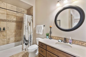 A bathroom with a bathtub, toilet, vanity with a mirror, and a shower curtain with a butterfly design.