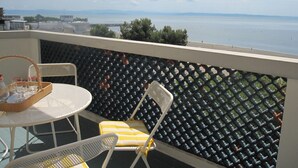 A balcony with a table and chairs, overlooking a body of water and distant land. - Adorable Seaview Flat at Grado Pineta (Grado)