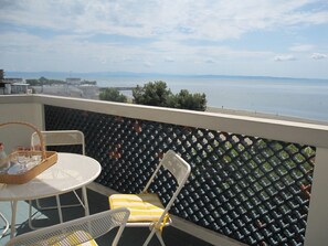A balcony with a table, chairs, and a view of the sea.