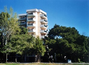 A multi-story building with balconies, surrounded by trees.