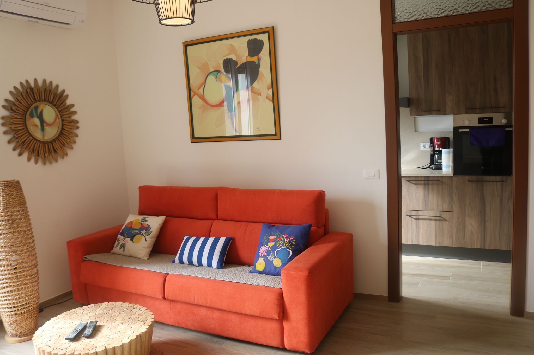 Un soggiorno con un divano arancione, un tavolino rotondo e un quadro appeso al muro.