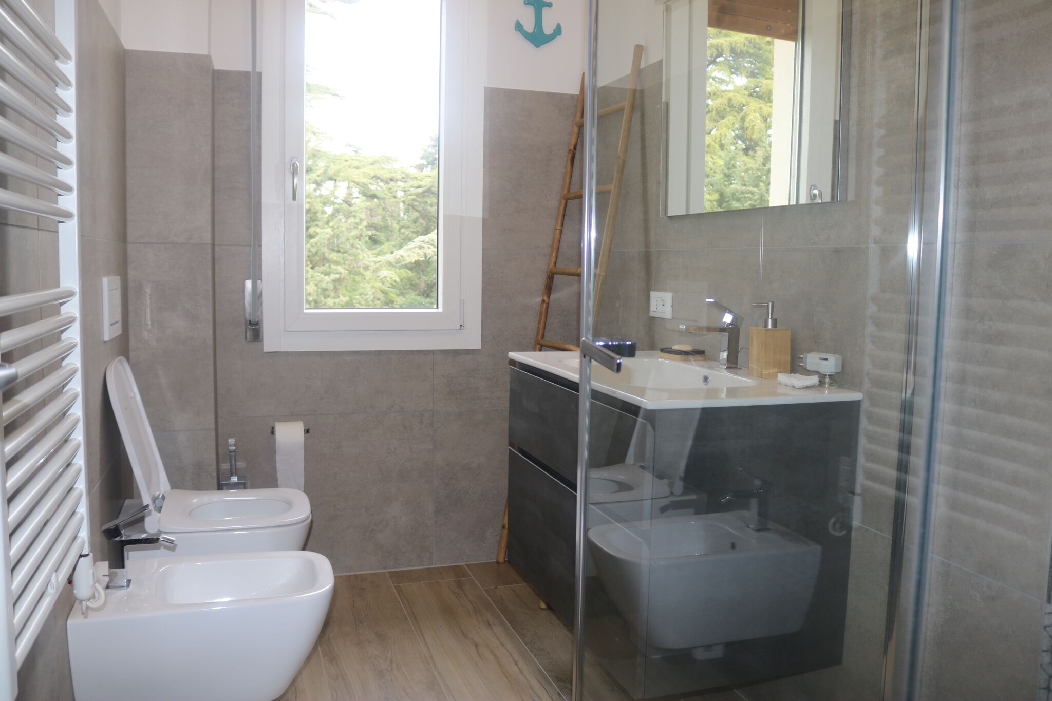 Un baño moderno con inodoro, bidé y ducha con mampara de vidrio.
