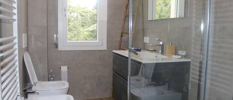 Un baño moderno con inodoro, bidé y ducha con mampara de vidrio.