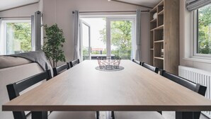 A dining area with a long table, chairs, a plant, and a view through large windows. - Shoreline - a spacious, well appointed lodge overlooking Christchurch Harbour. (Christchurch)