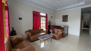 A spacious living room with two sofas, a coffee table, and a red curtain.